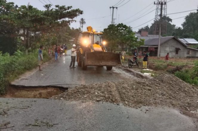 
 ? Alat berat sedang melakukan penimbunan jalan yang amblas.