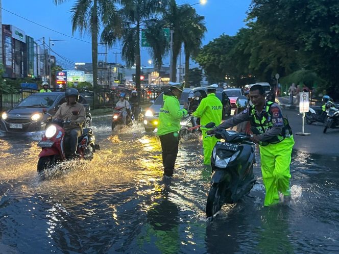 
 📸 Personel Ditlantas Polda Riau mengatur arus lalu lintas di tengah genangan air di Jalan Jenderal Sudirman, Pekanbaru.